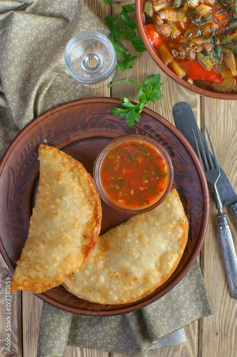 chebureks with tomato sauce on wooden background