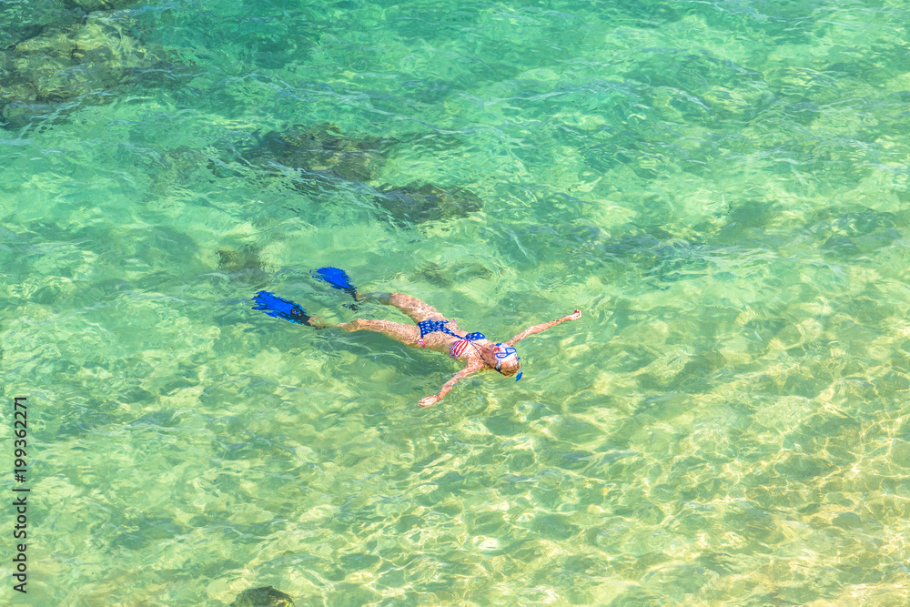 Woman snorkeling over coral reef in Hanauma Bay Nature Preserve, Oahu, Hawaii, USA. Female lying above the crystalline water in tropical sea with american flag bikini. Watersport activity in Hawaii.