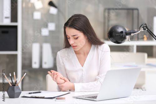Quadro em tela Young woman suffering from wrist pain in office