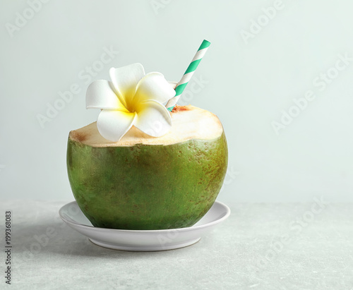 Fresh green coconut with drinking straw and flower on white background