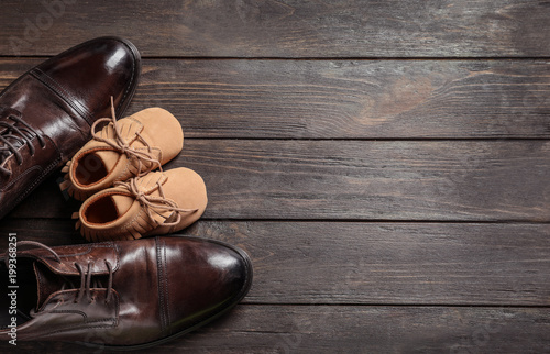 Obraz na plátně Flat lay composition with big and small shoes on wooden background