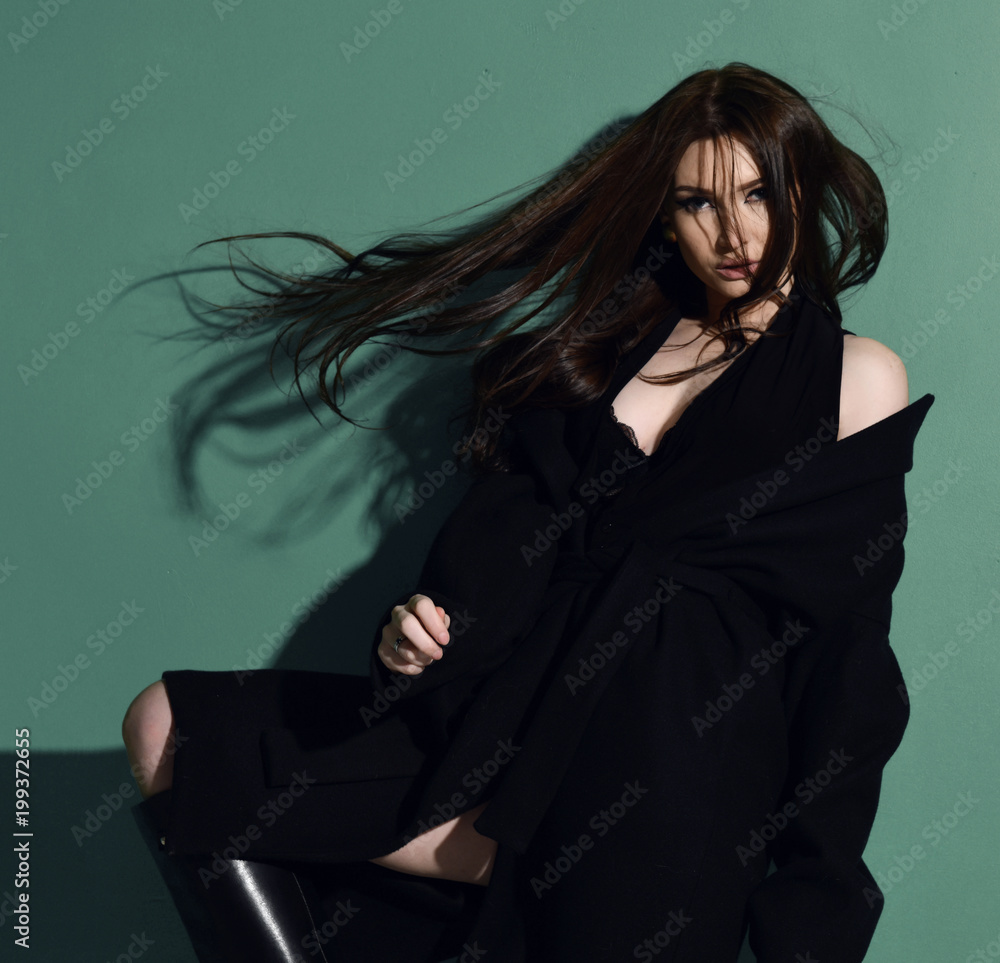 Fototapeta premium Beautiful brunette woman with long windy hair posing on green mint