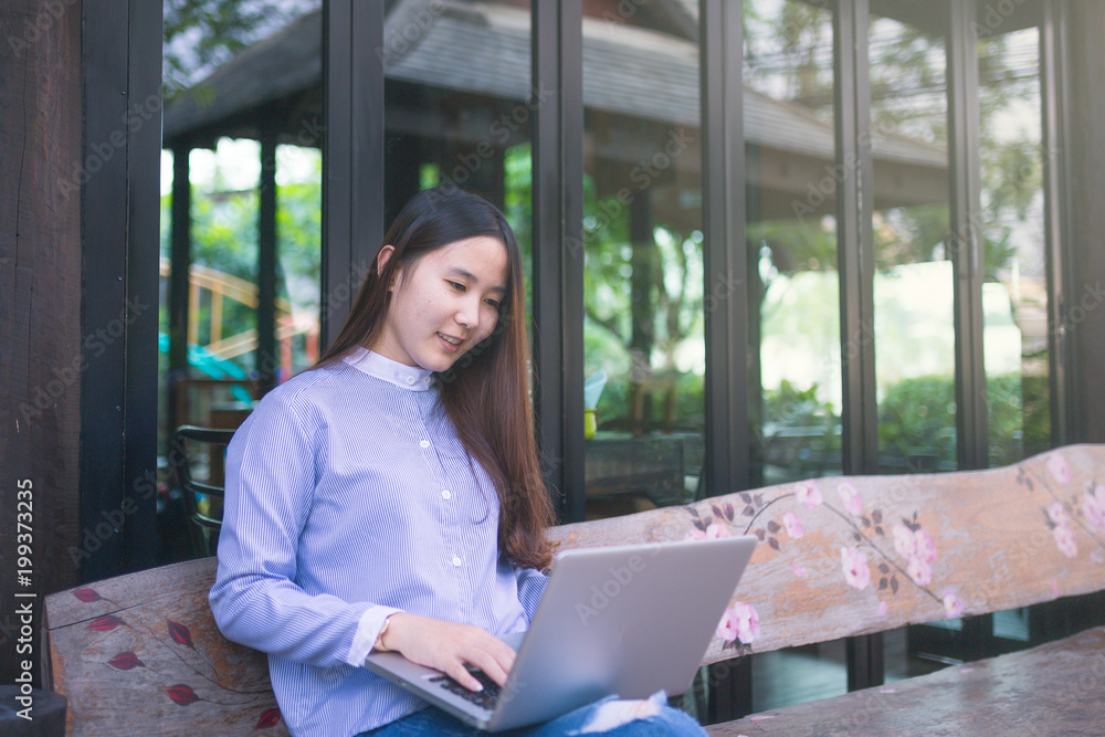 Women sitting and using smartphone and laptop on the table and she is feeling happiness at garden or cafe shop. Women sitting and using smartphone and laptop on the table and she is feeling happiness at garden or cafe shop.