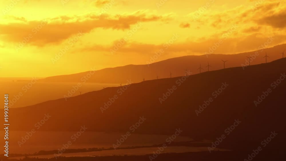 Wind turbines highlighted by a glorious sunset over mountains and sea Wind turbines highlighted by a glorious sunset over mountains and sea