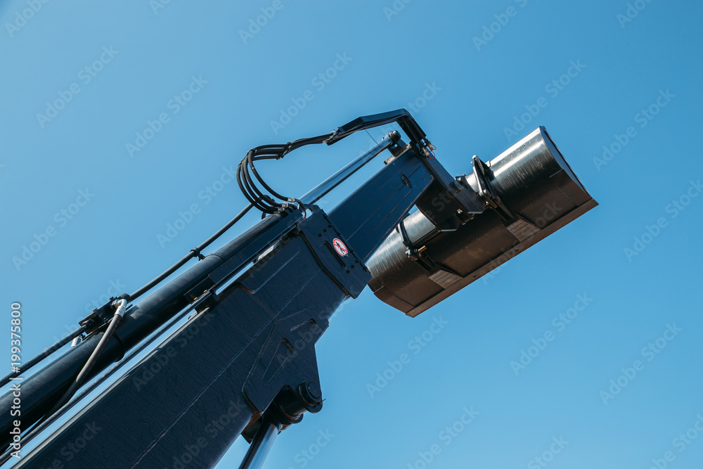 Boom of the excavator with bucket on blue sky background Boom of the excavator with bucket on blue sky background