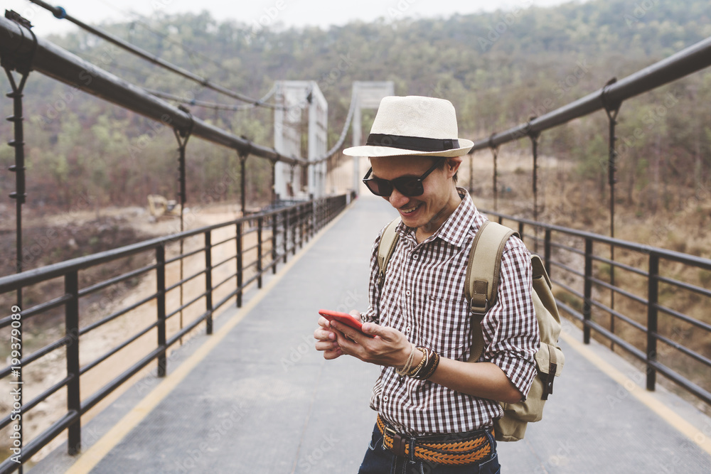 Young man traveller using mobile phone on bridge. Young man traveller using mobile phone on bridge.