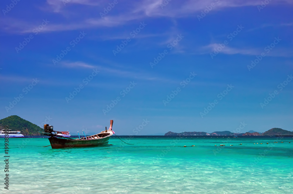 Landscape with wooden fishing longtail boat at noon tropical sea with turquoise water. Seascape Concept of aboriginal life in Asia Landscape with wooden fishing longtail boat at noon tropical sea with turquoise water. Seascape Concept of aboriginal life in Asia