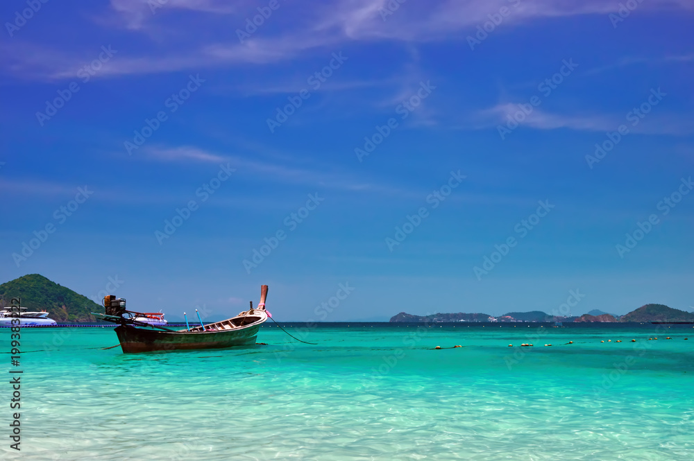 Landscape with wooden fishing longtail boat at noon tropical sea with turquoise water. Seascape Concept of aboriginal life in Asia