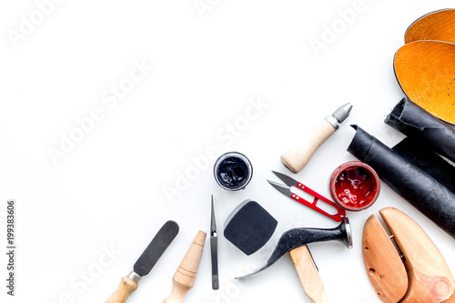 Work desk of shoemaker with instruments, wooden shoe and leather. White background top view copy space photo