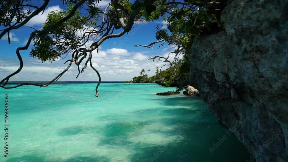 Glide past cliff into beautiful ocean at Lifou tropical island beach, New Caledonia. Glide past cliff into beautiful ocean at Lifou tropical island beach, New Caledonia.