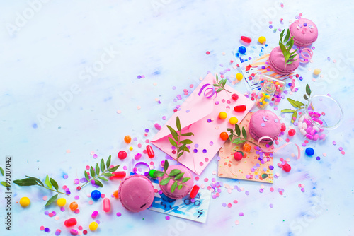 Invitation and love letter concept with copy space. Pink envelop with macarons, candies and confetti on a light background. Creative party flat lay.