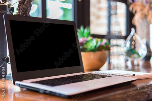 Mockup image of laptop with blank white screen on wooden table of In the coffee shop.