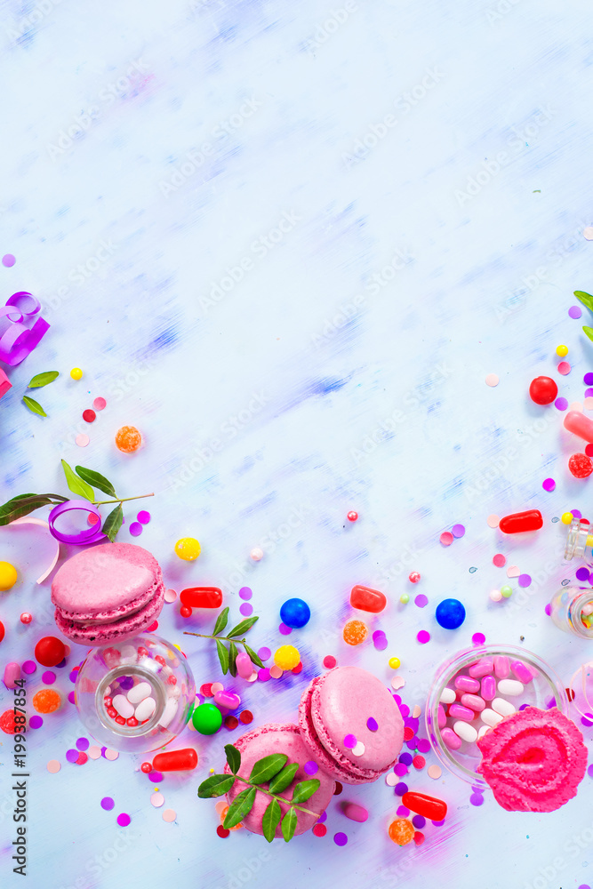 Colorful celebration flat lay with party supplies, confetti and sweets. Pink macarons in an afterparty mess.