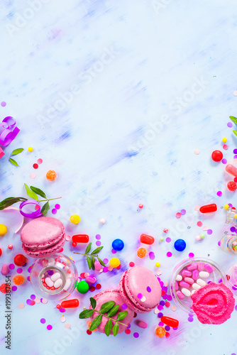 Colorful celebration flat lay with party supplies, confetti and sweets. Pink macarons in an afterparty mess.