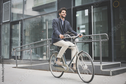Smiling young businessman driving bike on street.