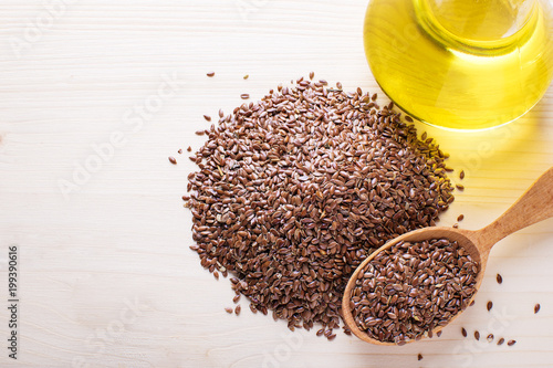Bild auf Leinwand flax seeds in a wooden spoon, next flaxseed oil, on an old board