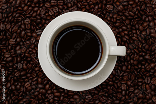 Top view  a cup of coffee on coffee beans background.