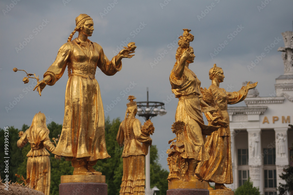 Golden statue in Moscow park. Women with a flowers in her hand