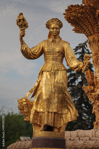 Golden statue in Moscow park. A woman with a sheaf in her hand