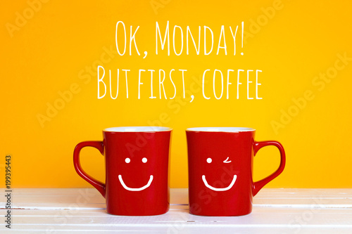 Two red coffee mugs with a smiling faces on a yellow background with the phrase Ok, mondey, but firrst coffee.