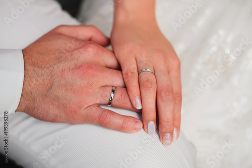 hands of loving couple bridegroom and bride close-up with gold rings on white background