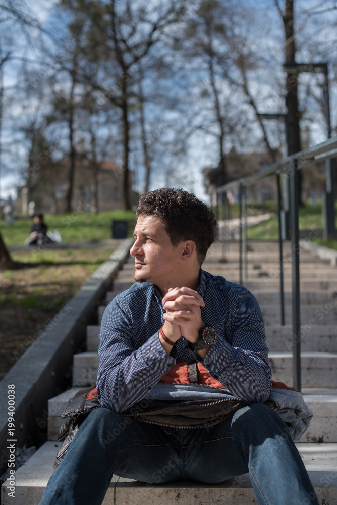 young man sitting on steps in park young man sitting on steps in park