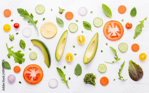 Fototapeta Naklejka Na Ścianę i Meble -  Food pattern with raw ingredients of salad, lettuce leaves, cucumbers, tomatoes, carrots, broccoli, basil ,onion and lemon flat lay on white wooden background.