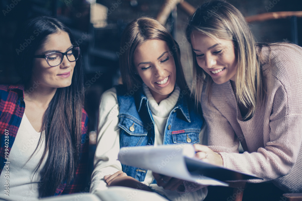 Three students girl reading file together indoors. Close up. Three students girl reading file together indoors. Close up.