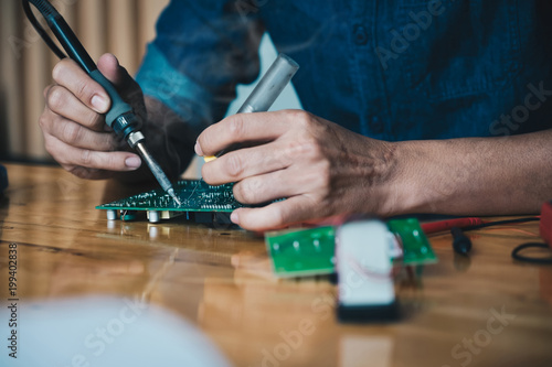 Close up of the hand men hold tool repairs electronics manufacturing Services, Manual Assembly Of Circuit Board Soldering.