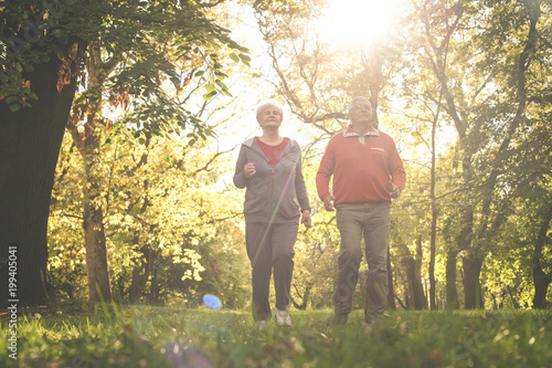 Active seniors couple in sports clothing jogging together in park. © Mladen