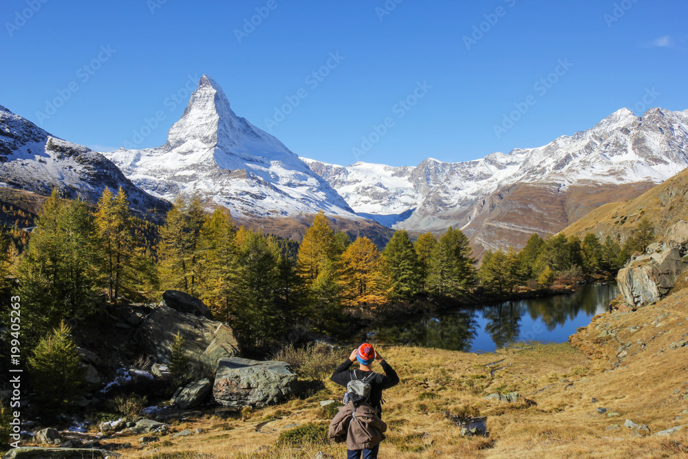 Hiker is photographing Matterhorn at the Grindjisee Lake. Matterhorn is the most famous Alps peak in Switzerland