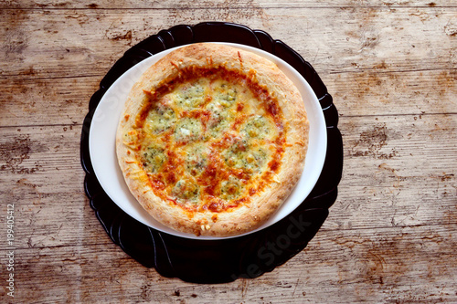 Pizza margherita, geschmückt einfach in den Farben der italienischen  weiß aus Mozzarella, rot aus Tomatensauce  holzem hintergrund