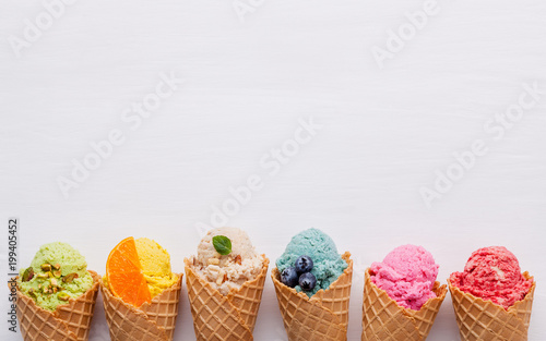 Tablou canvas Various of ice cream flavor in cones blueberry ,strawberry ,pistachio ,almond ,orange and cherry setup on white wooden background