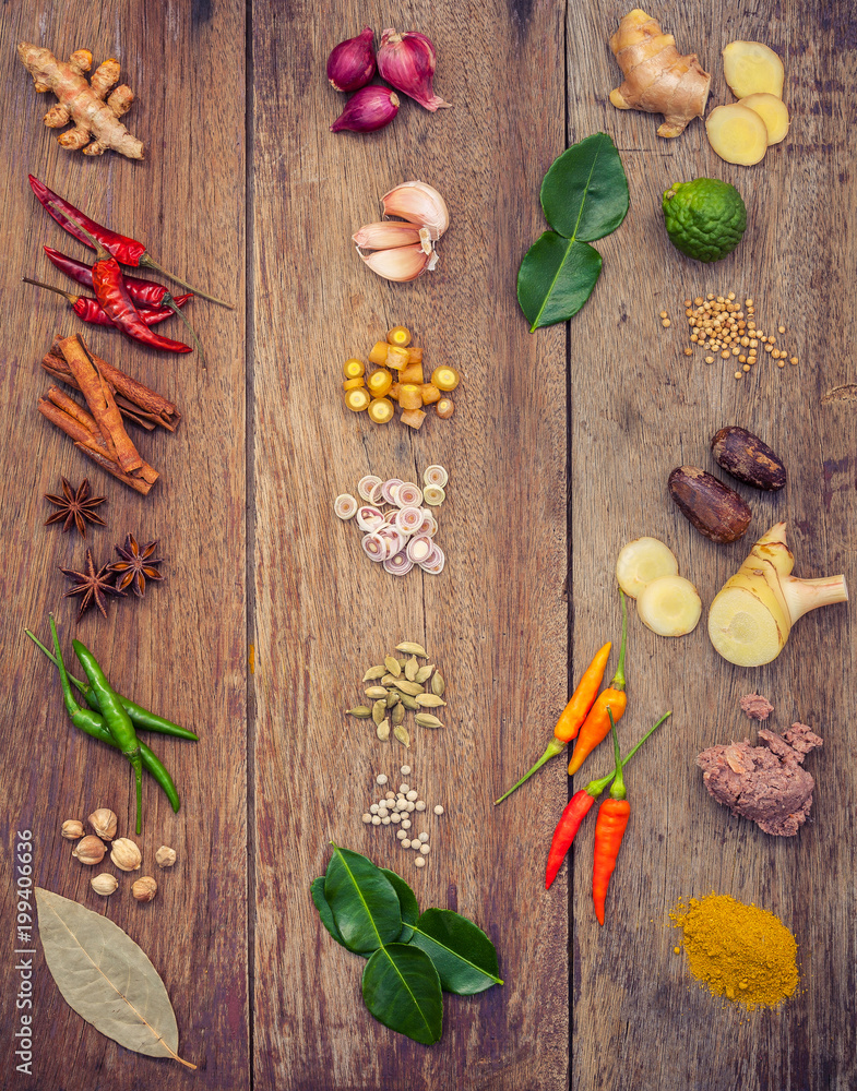 Fototapeta premium Various of Thai food Cooking ingredients and spice red curry paste ingredient of thai popular food on rustic wooden background. Spices ingredients chilli ,pepper, garlic and Kaffir lime leaves .