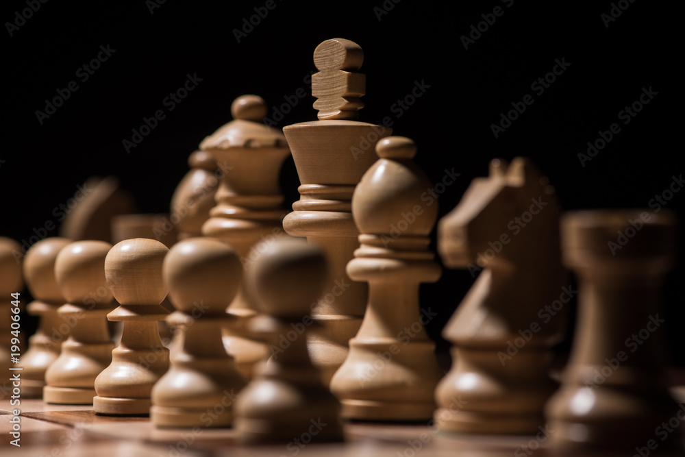 ordered white wooden chess figures on chessboard isolated on black, business concept