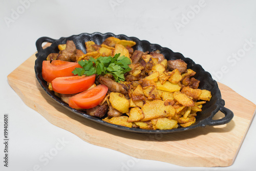 potatoes fried meat in a frying pan on a tree on a white background