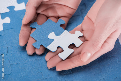 cropped image of businesswoman assembling blue and white puzzles together, business concept