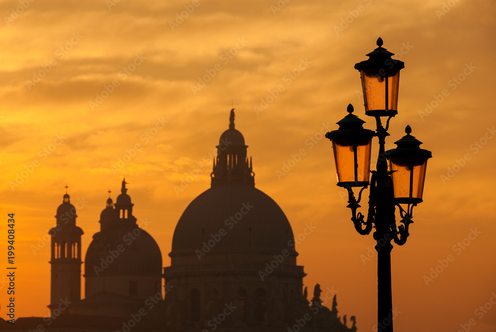 Old traditional Venice street lamps at sunset with Salute Basilica old domes in a romantic atmosphere