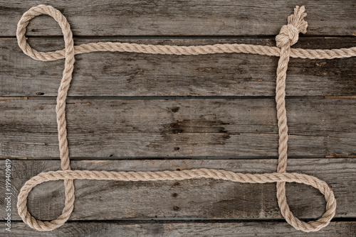 Fototapeta Naklejka Na Ścianę i Meble -  top view of nautical rope with knot on grunge wooden surface