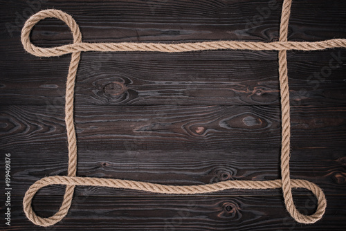 Fototapeta Naklejka Na Ścianę i Meble -  top view of brown nautical rope on dark wooden surface