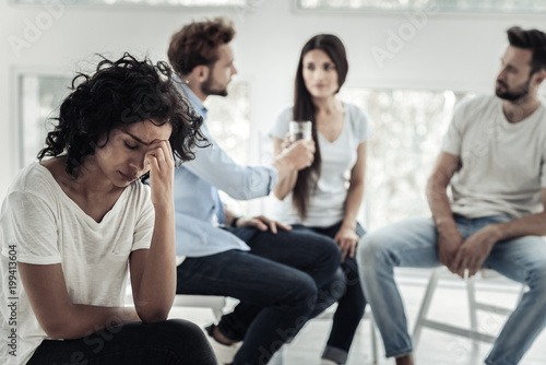 So sad. Depressed nice young woman holding her forehead and thinking about her problems while having a depression