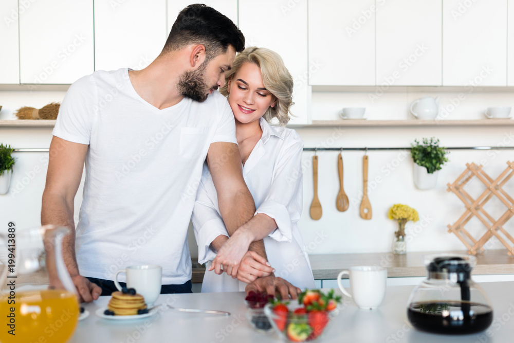 beautiful young couple hugging while having breakfast together