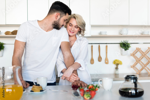 beautiful young couple hugging while having breakfast together