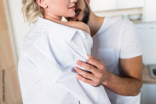 cropped shot of smiling young man embracing sexy girlfriend