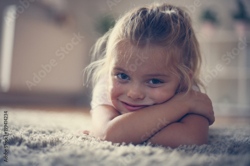 Little girl looking at camera. Little girl at home , lying on floor and looking at camera.