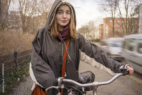 Canvas Print portrait of a smiling young woman who is pushing her bicycle