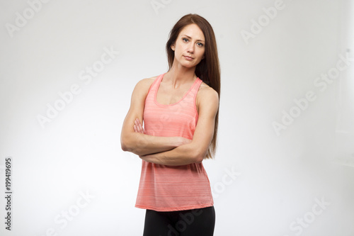 Fitness woman portrait on grey background. Smiling happy female fitness model looking at camera. Fresh beautiful multi-racial Caucasian fitness girl