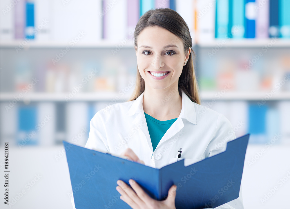Smiling doctor writing on a clipboard Smiling doctor writing on a clipboard