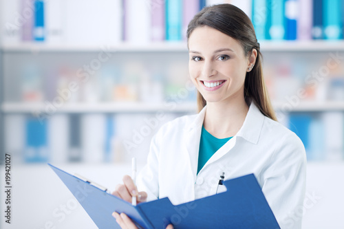 Smiling doctor writing on a clipboard