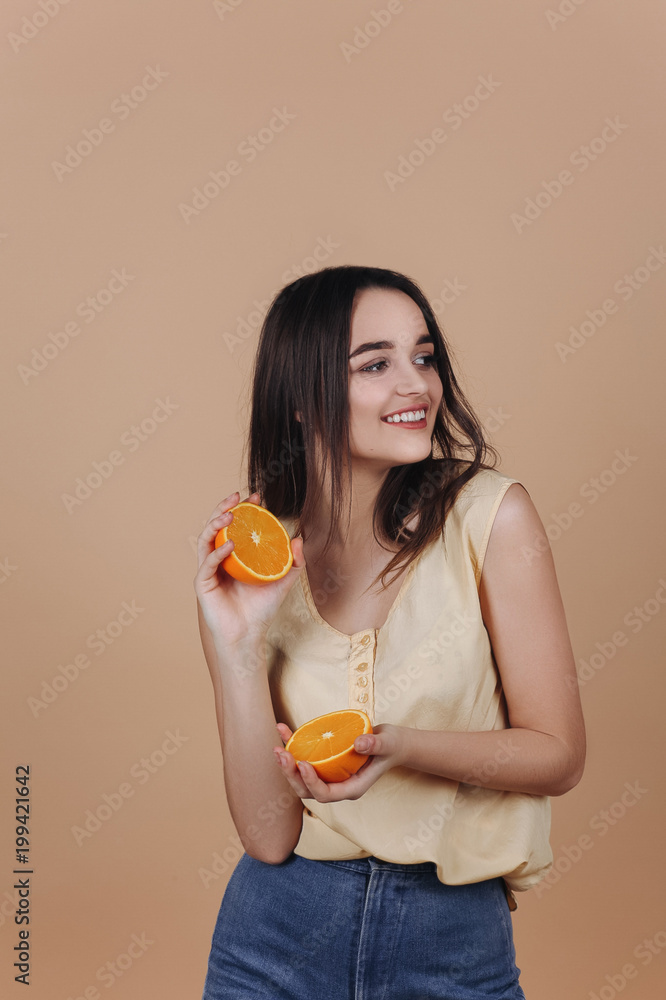 Charming young woman with an orange smiles posing in the studio Charming young woman with an orange smiles posing in the studio